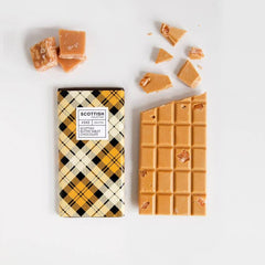 Scottish Tablet Chocolate Bar, 100g next to pieces of traditional Scottish tablet on a white background.