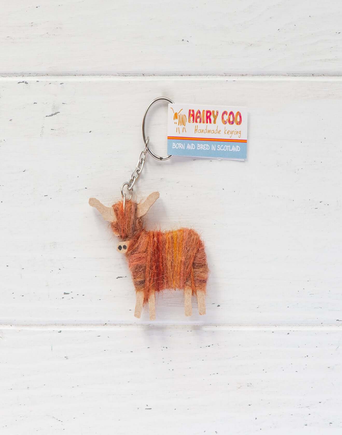 Handmade Highland Cow Keyring - Born and Bred in Scotland attached to a keychain with colorful wool texture.
