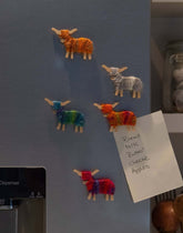 Handmade Highland Cow Magnet - Born and Bred in Scotland on a fridge, colorful cow designs holding a shopping list.