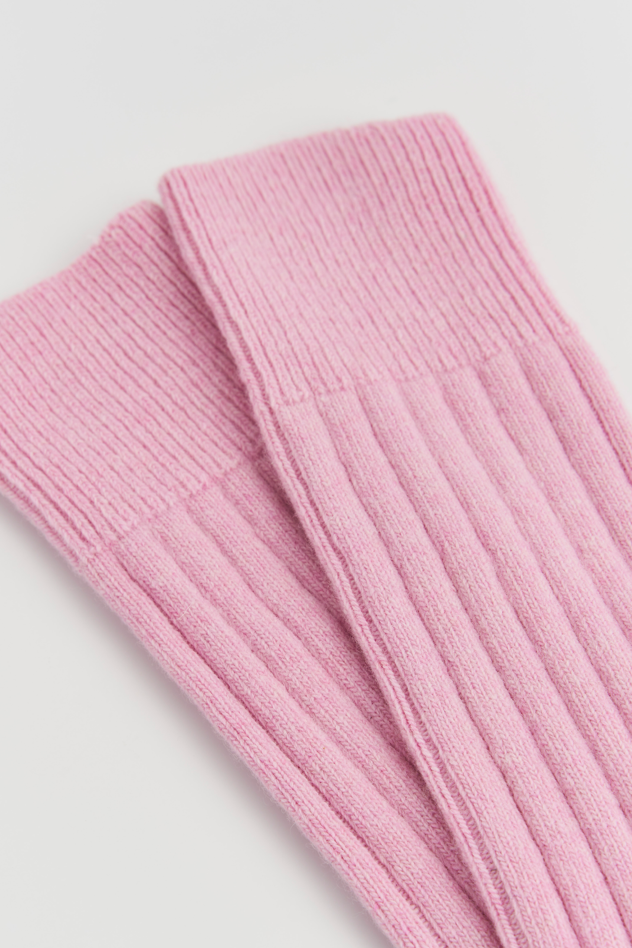 Pink merino bed socks in a soft ribbed design, perfect for warmth and comfort.