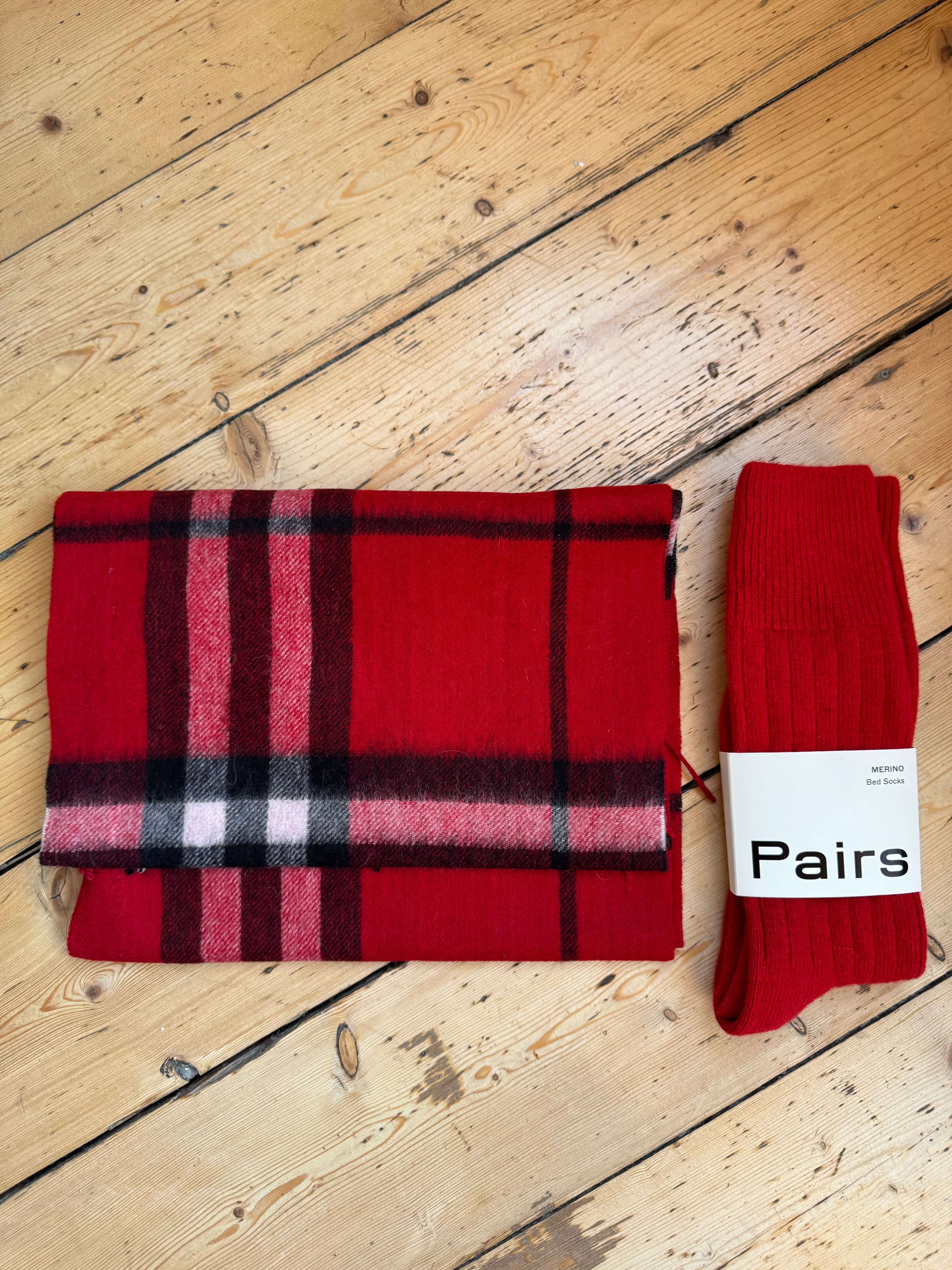 Red plaid scarf and socks on a wooden surface 