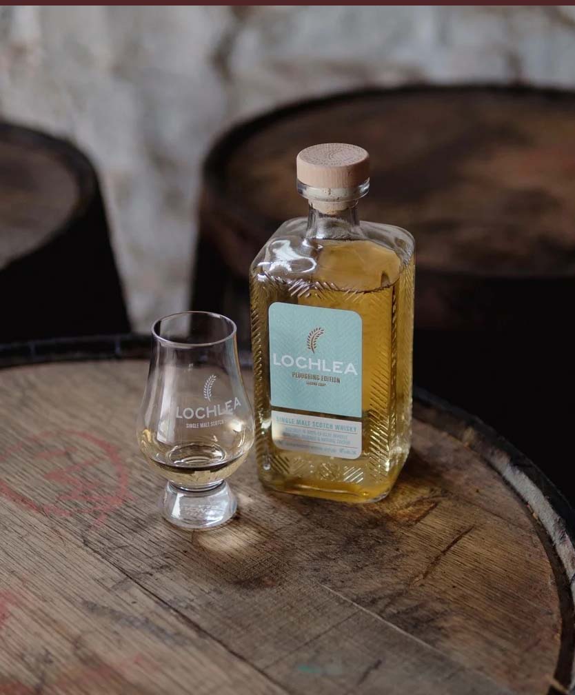 Lochlea whisky bottle and glass on a wooden barrel